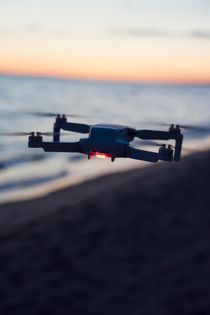 DJI Mini 2 flying with a blurred ocean sunset background